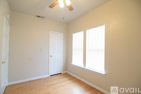 A room with a ceiling fan and two windows.
