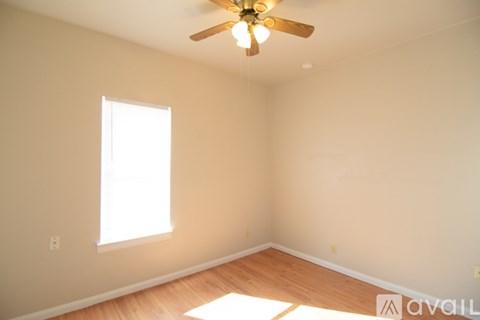 A room with a ceiling fan and a window letting in sunlight.