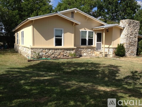 A house with a stone pillar and a stone wall in the front yard.