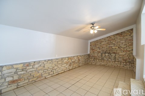A room with a stone wall and a ceiling fan.