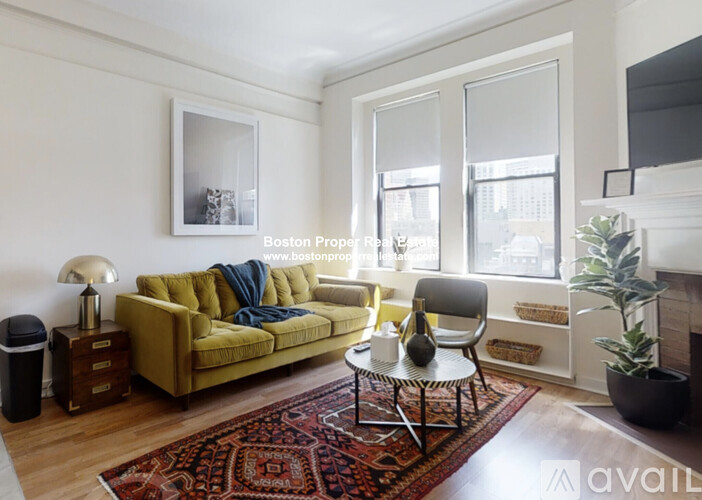 A living room with a yellow couch and a red rug.