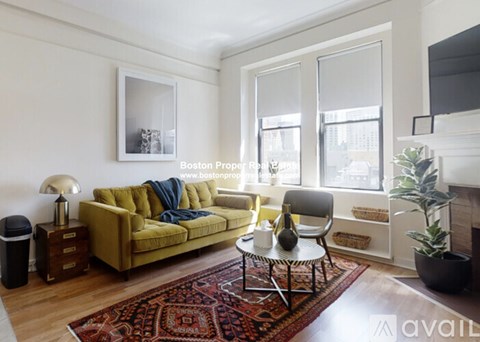 A living room with a yellow couch and a red rug.