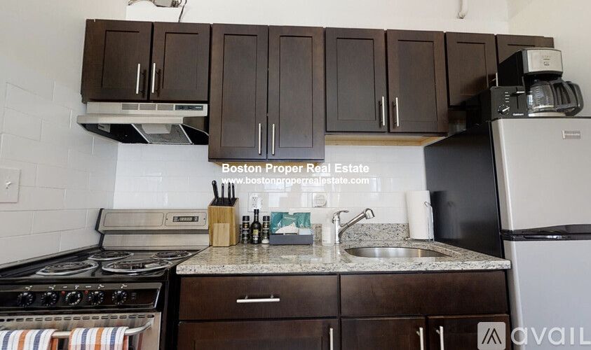 A kitchen with a stove, sink, and cabinets.