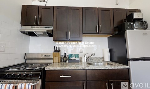 A kitchen with a stove, sink, and cabinets.