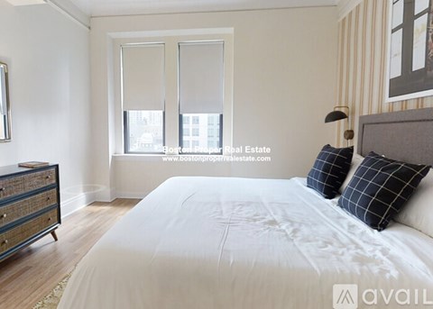 A bedroom with a large bed, a dresser, and a window with blinds.