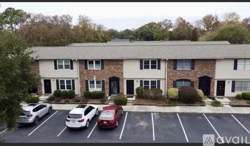 A parking lot with a building in the background and a car in the foreground.