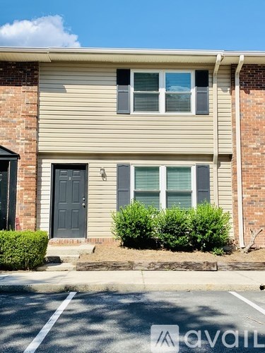 A two-story house with a grey front door and a small bush in front.