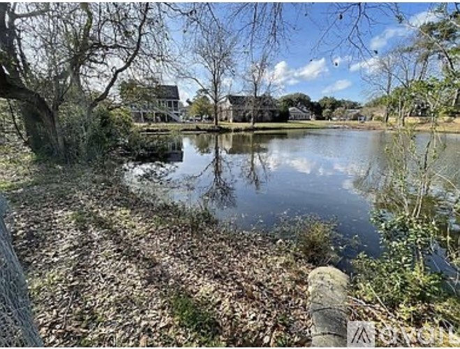 A serene lake surrounded by trees and a house in the distance.
