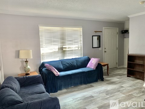 A living room with a blue couch and a lamp on a side table.