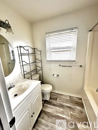 A bathroom with a toilet, sink, and a window with blinds.