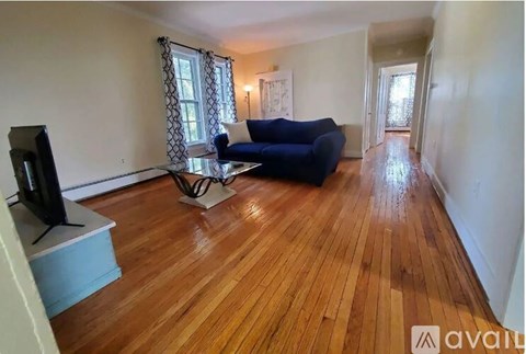 A living room with a blue couch and wooden floors.