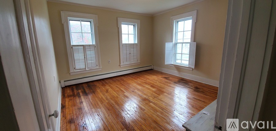 A room with wooden floors and three windows.
