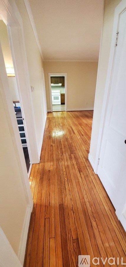 A long hallway with wooden floors and white walls.