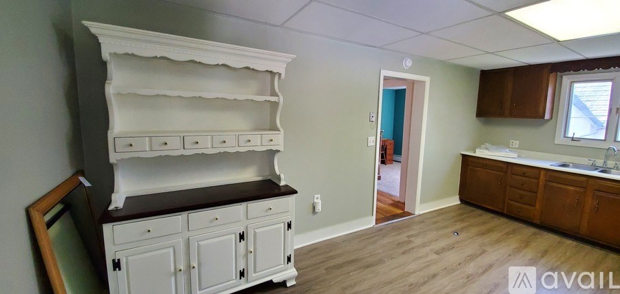 A kitchen with a white hutch and wooden cabinets.