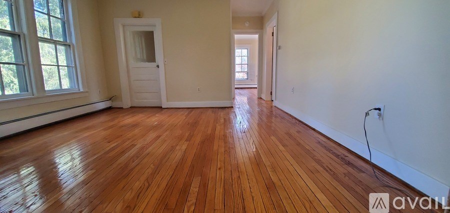 A room with wooden floors and a door on the left.