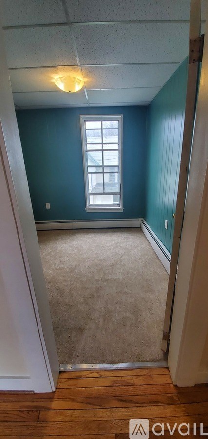 A room with a window and a carpeted floor.