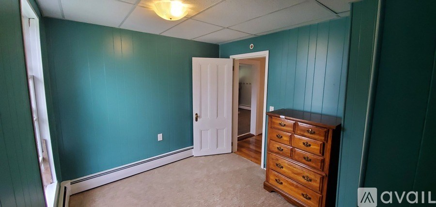 A room with a white door and a brown dresser.