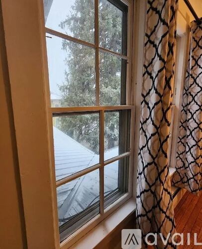 A window with a view of trees and a building outside.