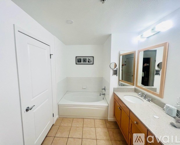 A bathroom with a tub, sink, mirror, and a towel rack.