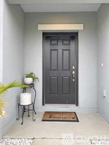 A black door with a gold handle and a mat that says "home" on the floor.