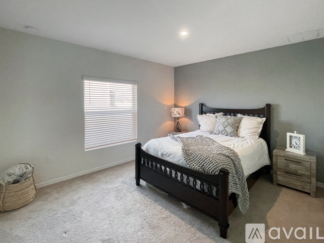 A bedroom with a large bed and a window with blinds.