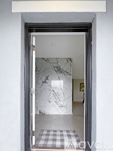 A doorway with a marble wallpaper and a checkered doormat.