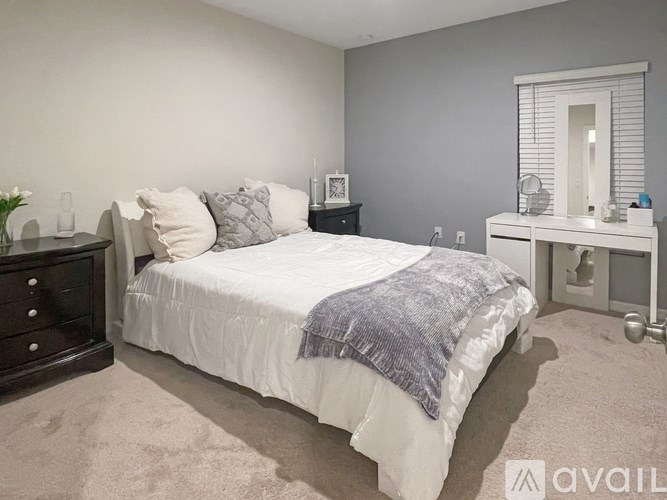 A bedroom with a bed, nightstand, and a mirror.