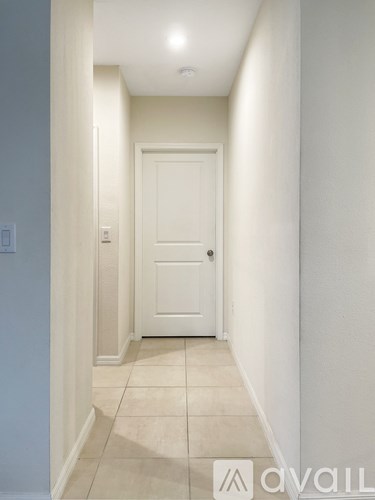 A hallway with a white door and tiled floor.