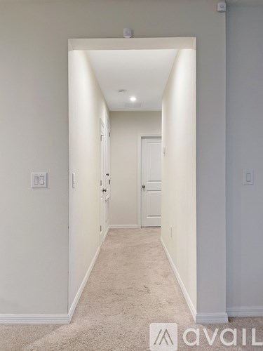 A hallway with a carpeted floor and white walls.