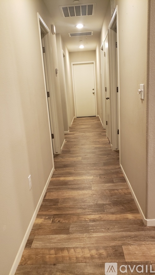 A long hallway with wood floors and white walls.