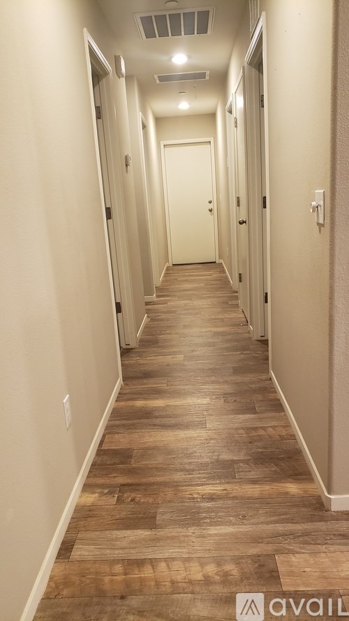 A long hallway with wood floors and white walls.