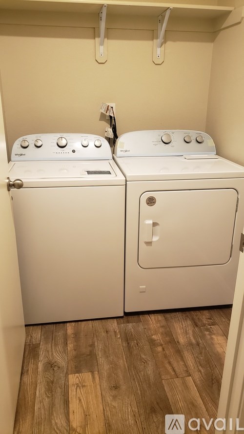 Two white front loading washing machines in a small laundry room.