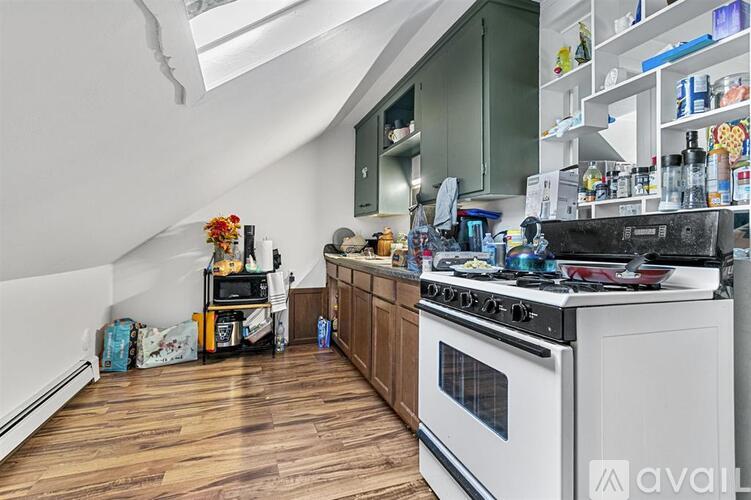 A kitchen with a white stove top oven and wooden floors.