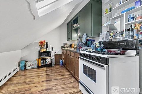 A kitchen with a white stove top oven and wooden floors.