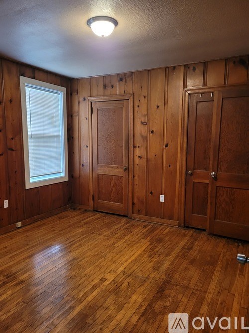 A room with wooden walls and floors and a window.