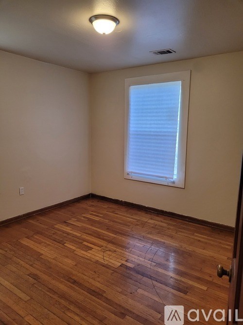 A room with wooden flooring and a window with blinds.