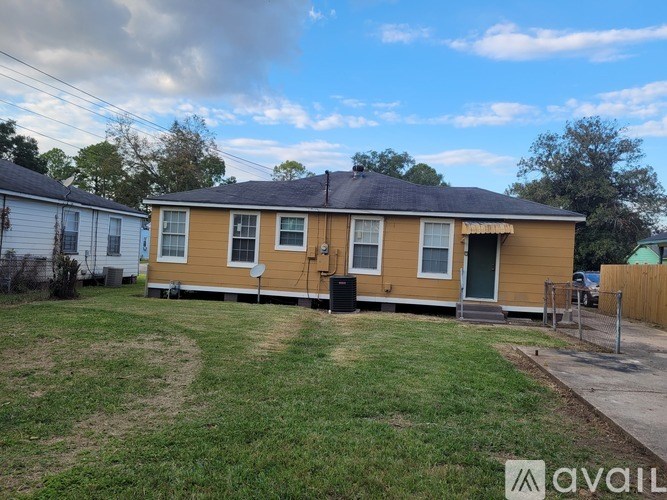 A yellow house with a black door and a green lawn.