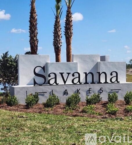 A sign that says Savanna Lakes in front of two palm trees.