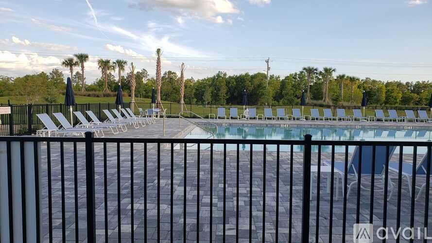 A pool area with sun loungers and a fence.