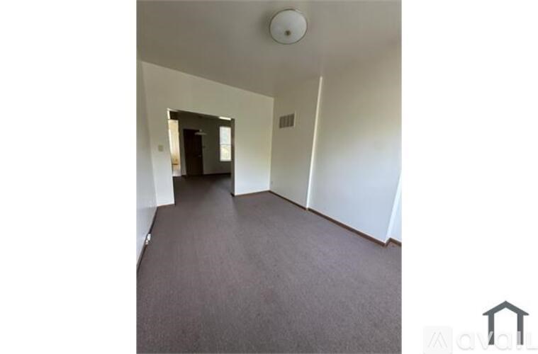 A hallway with a carpeted floor and white walls.