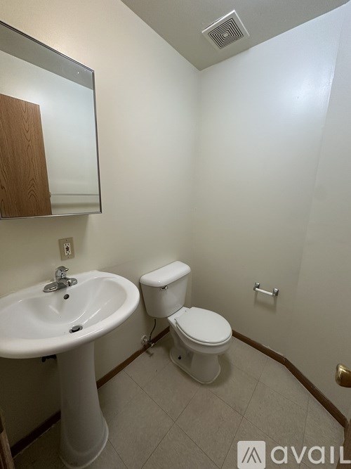 A bathroom with a toilet, sink, and mirror.