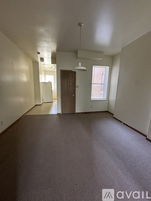 A carpeted room with a door and a window.