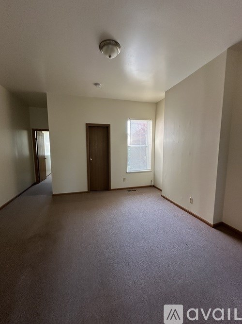 A spacious room with a carpeted floor and a window letting in natural light.