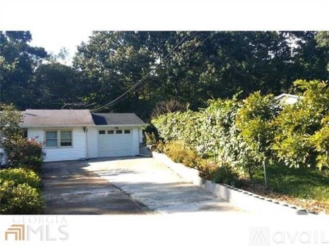A house with a white garage door is surrounded by greenery.