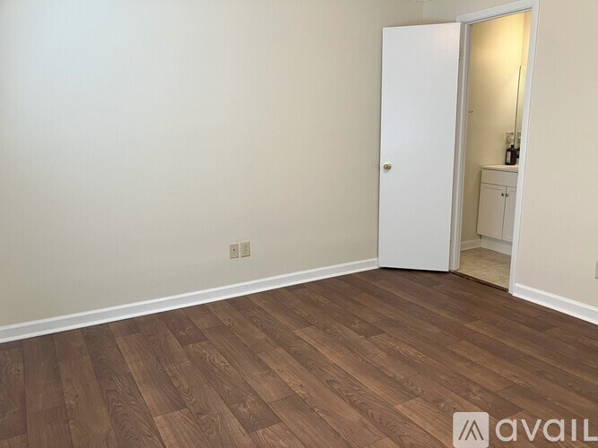 A room with a white door and wooden flooring.