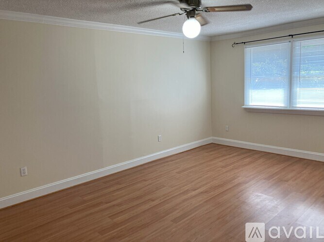 A room with a ceiling fan and wooden flooring.