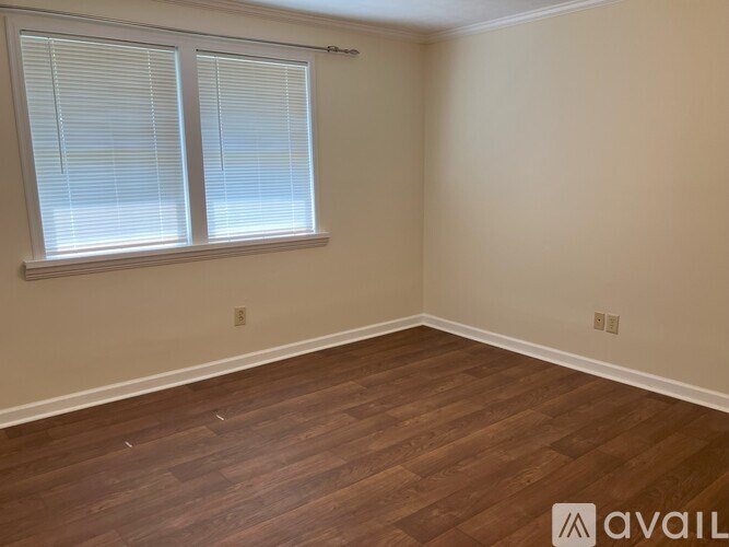 A room with wooden flooring and a window with blinds.