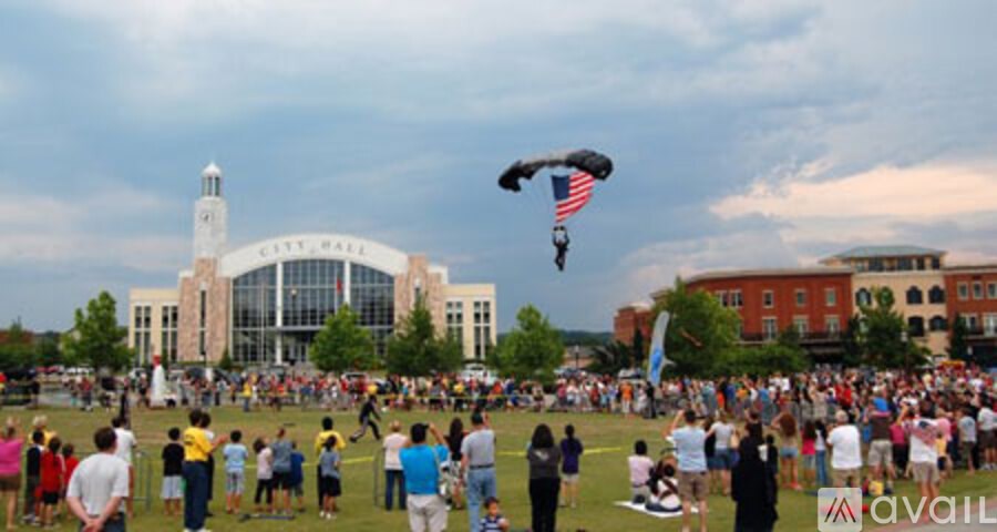 A large crowd of people are gathered in a field to watch a man fly a kite.