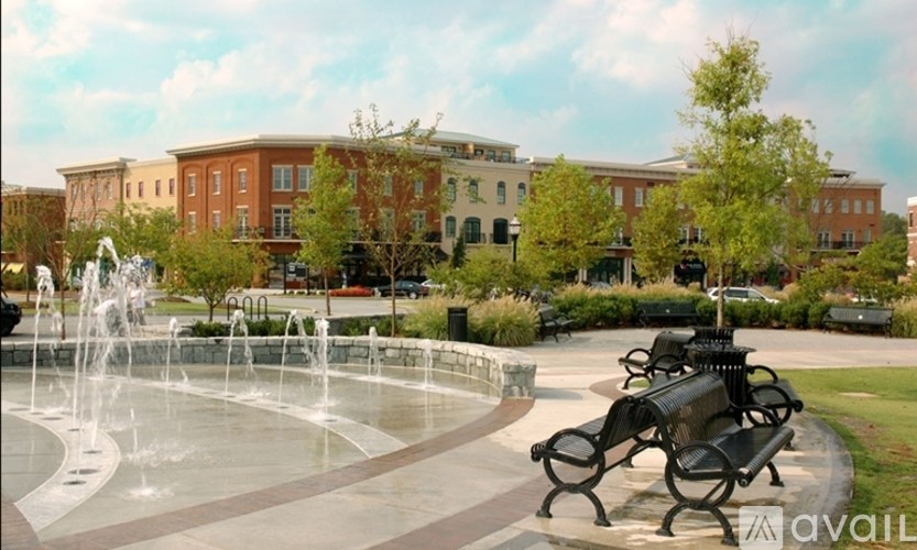 A fountain in the middle of a park with benches around it.