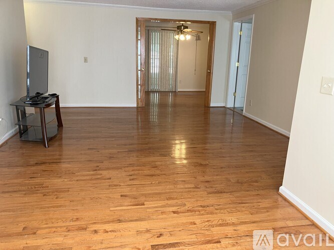 A living room with wooden floors and a television.